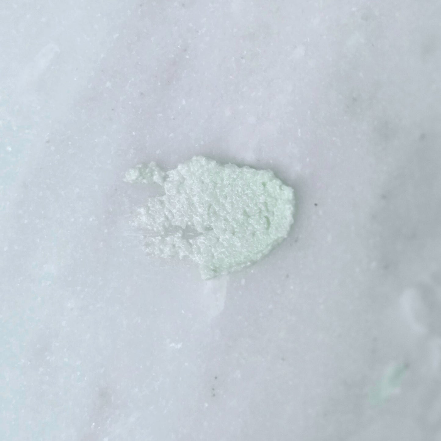 Smear of a green dead sea salt body scrub on a gray background