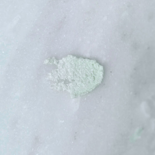 Smear of a green dead sea salt body scrub on a gray background