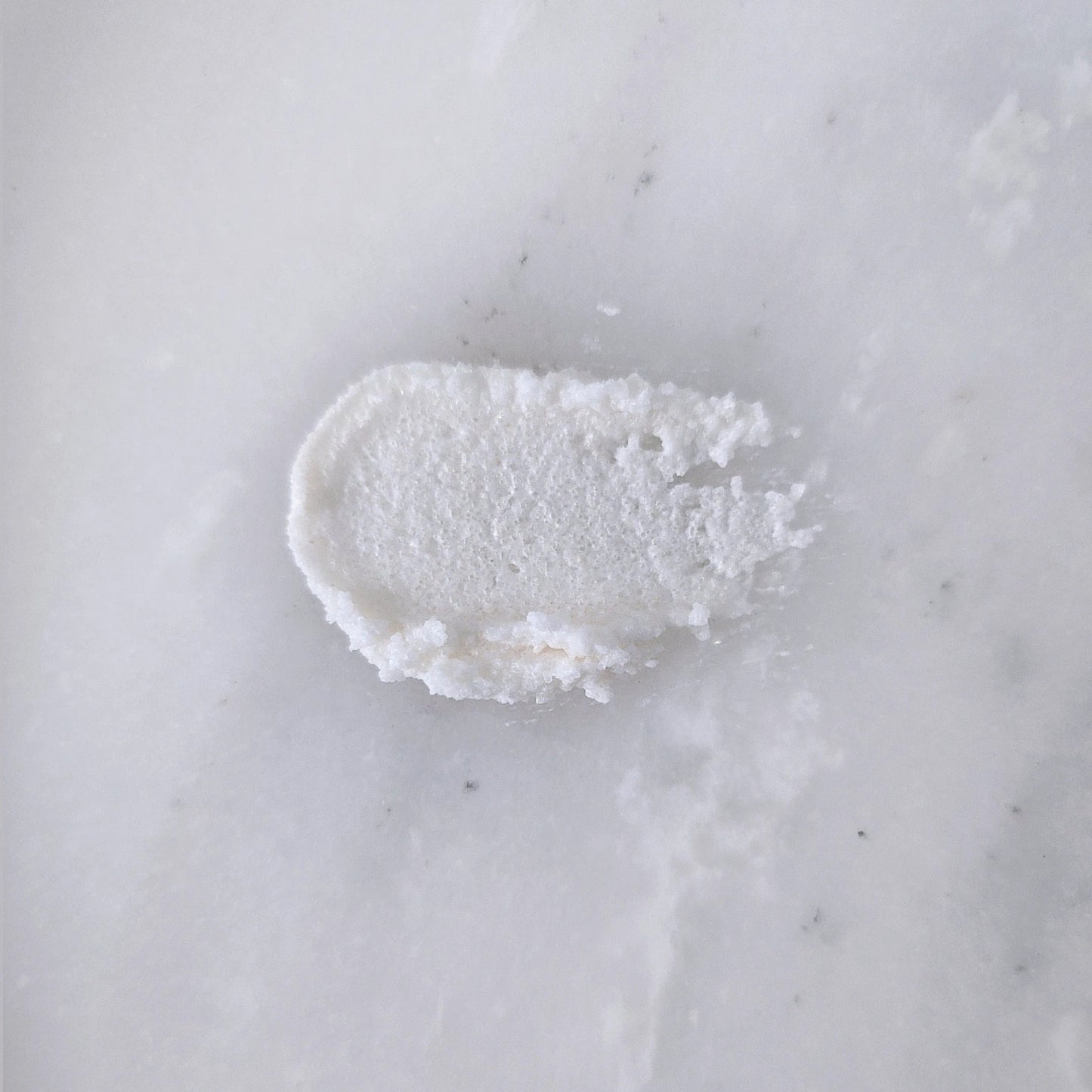 Smear of white sugar scrub on a marble surface