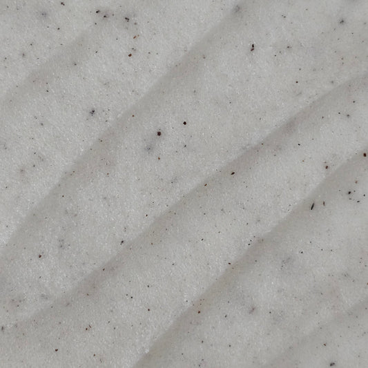 Close up of cream colored whipped sugar scrub texture with flecks of finely ground coconut shell