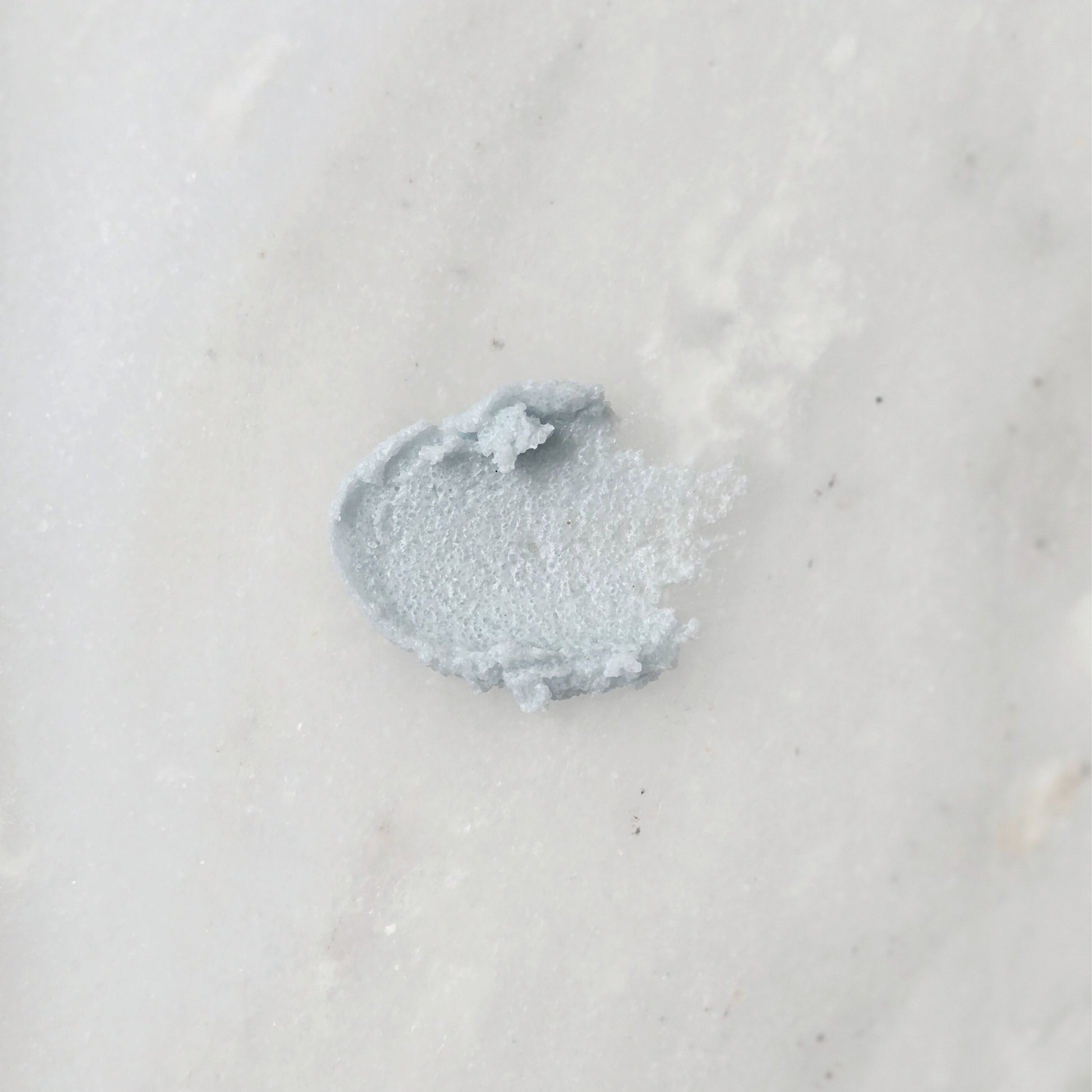 Smear of a blue sugar scrub on a marble background