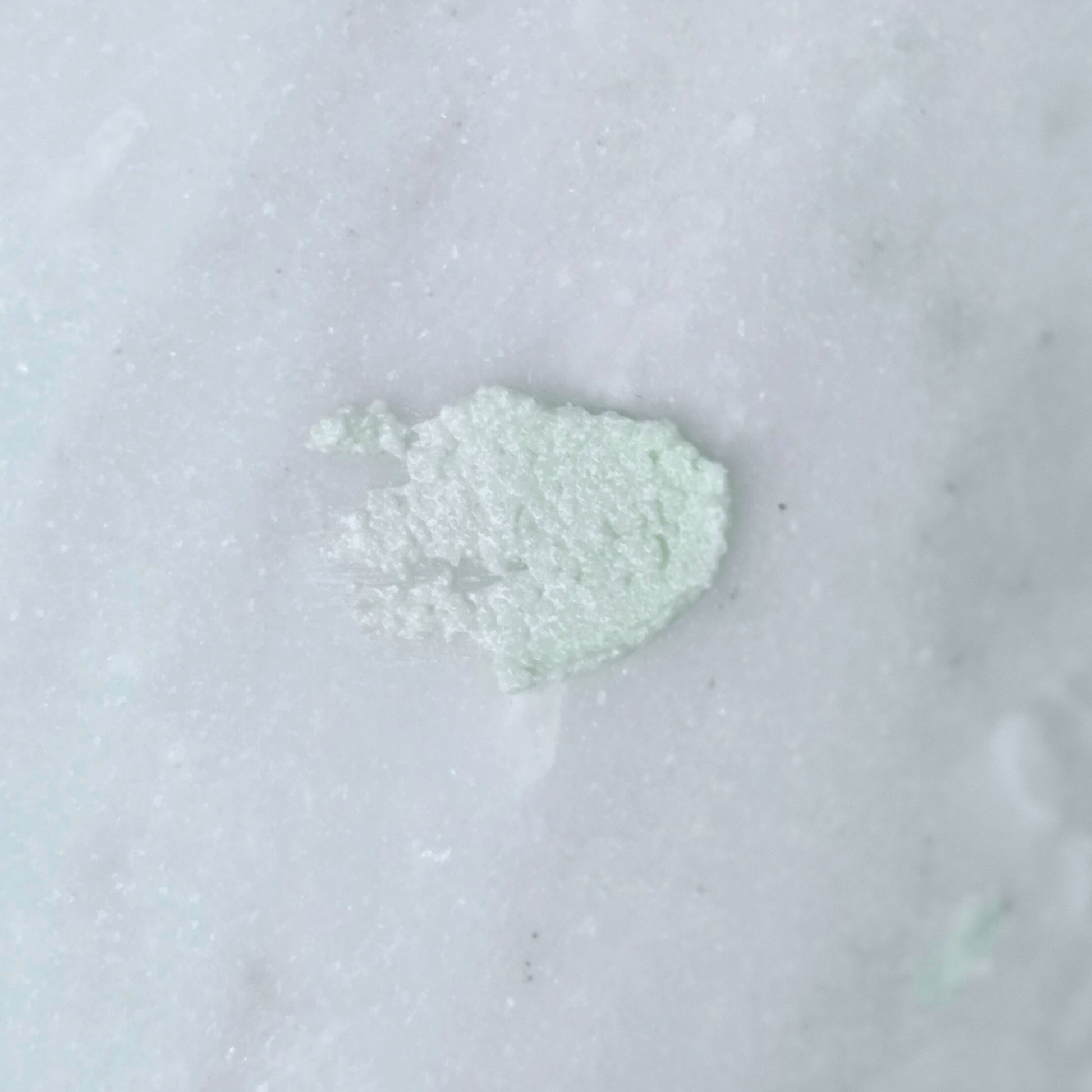 Smear of a green dead sea salt body scrub on a gray background