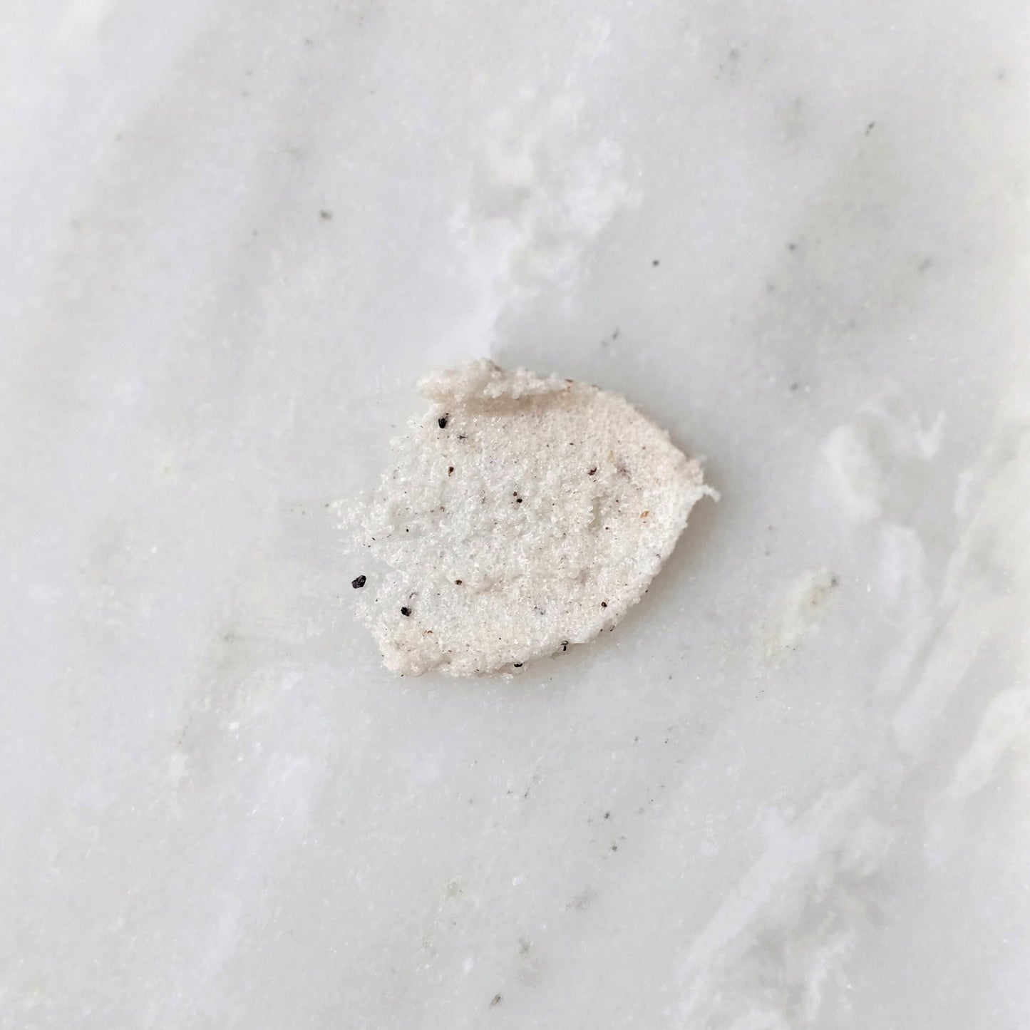 Smear of a sugar scrub with cupuacu seed on a marble background