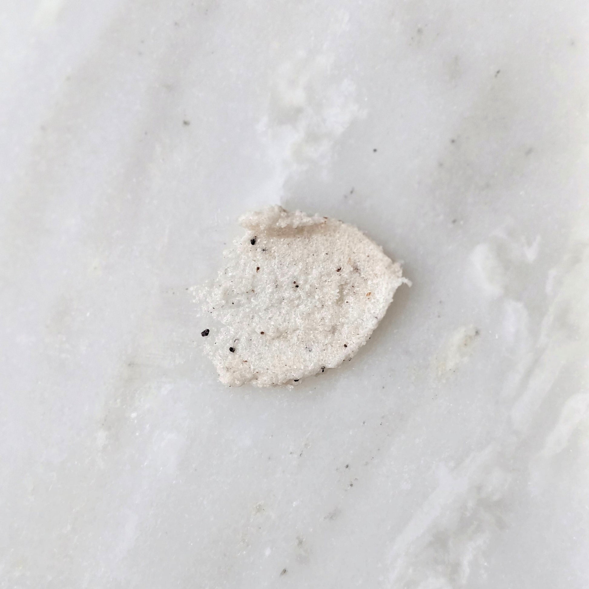 Smear of a sugar scrub with cupuacu seed on a marble background