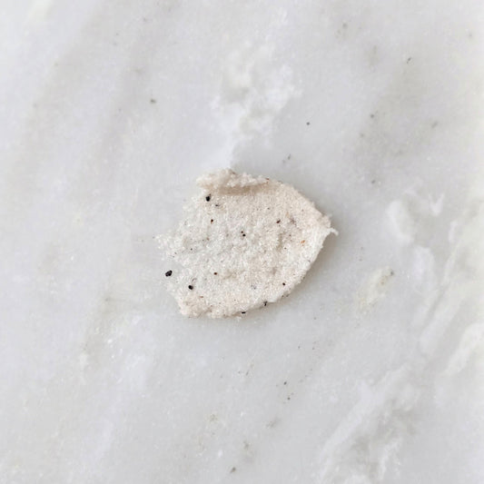 Smear of a sugar scrub with cupuacu seed on a marble background