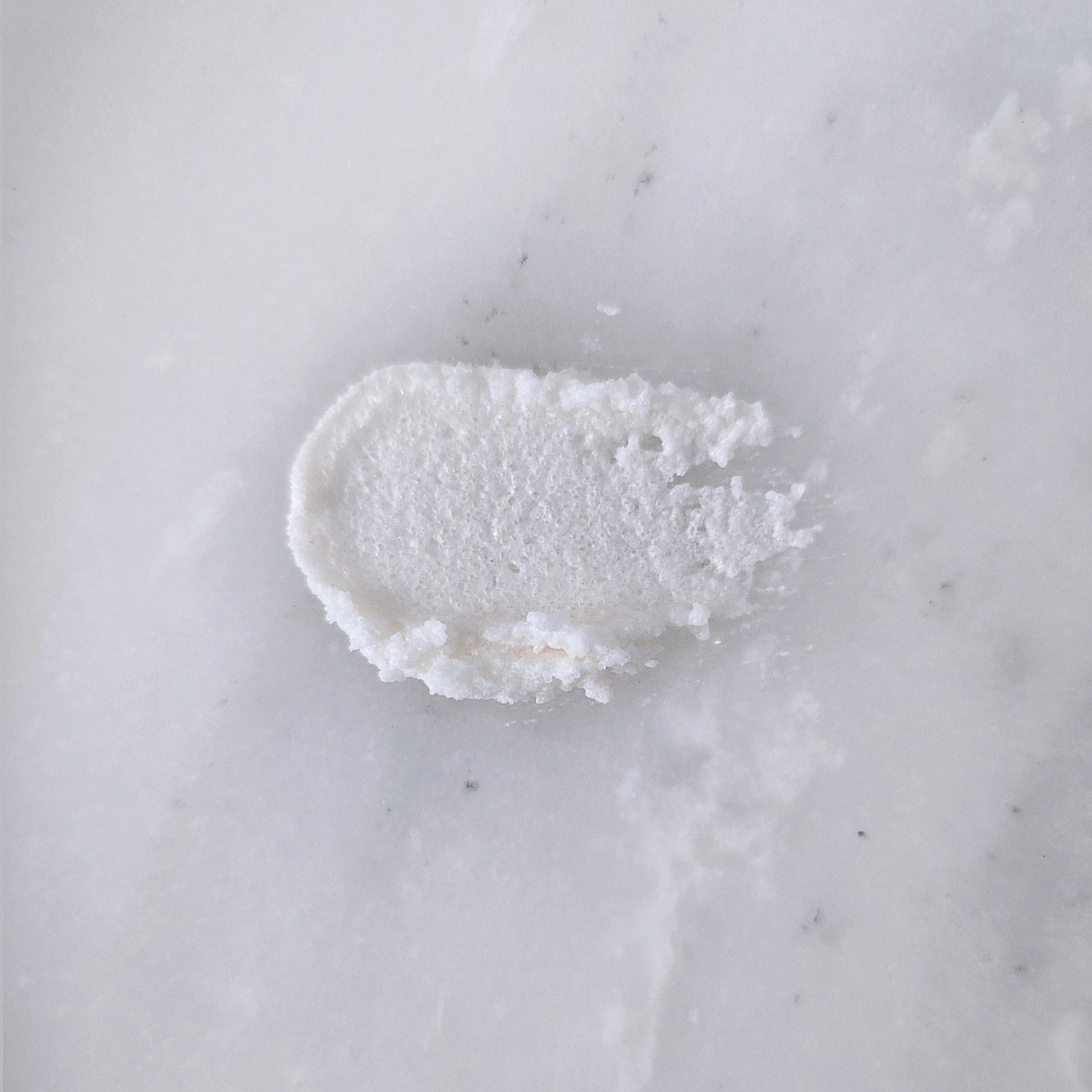 Smear of white sugar scrub on a marble surface