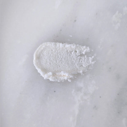Smear of white sugar scrub on a marble surface