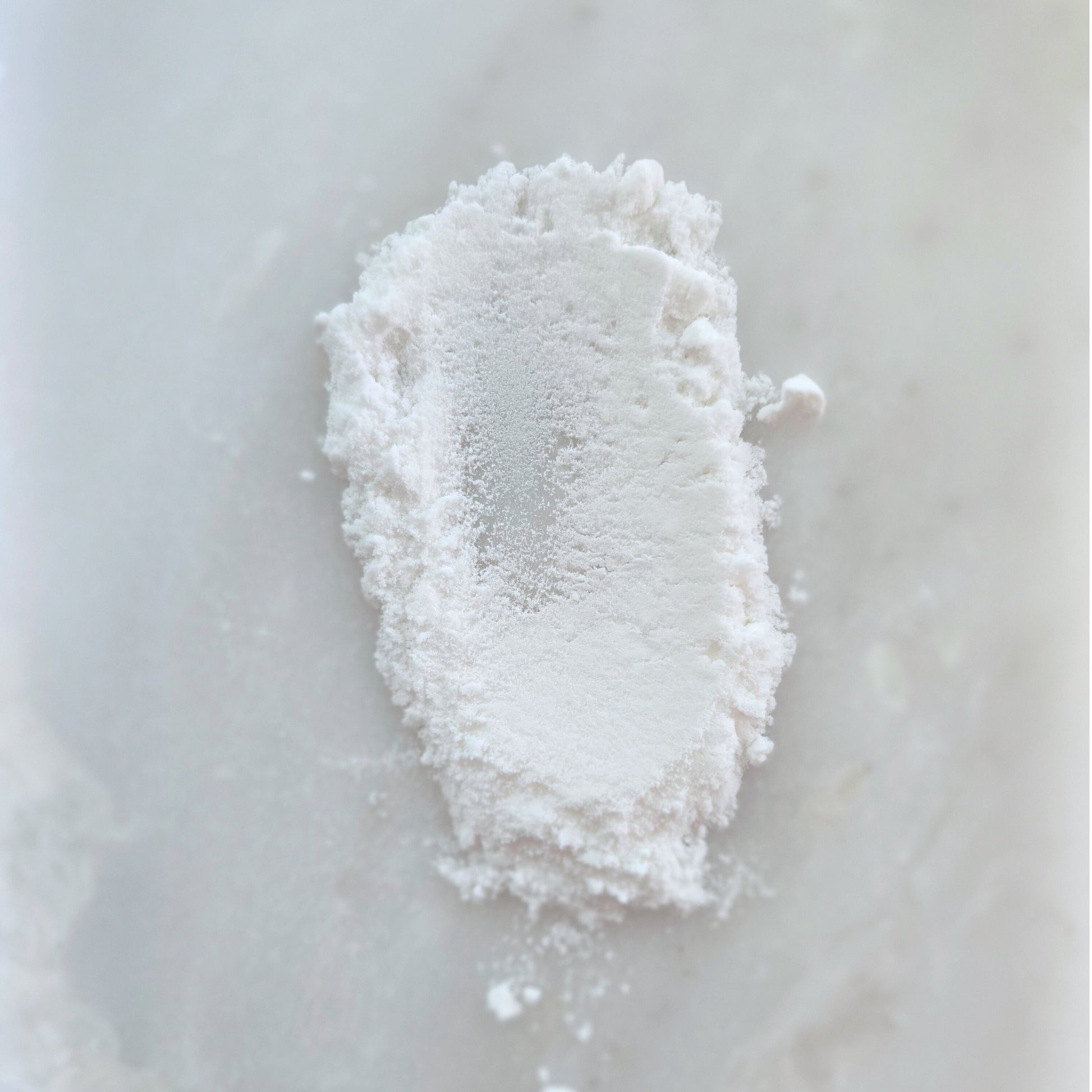 Clump of white coconut milk powder on a light gray surface