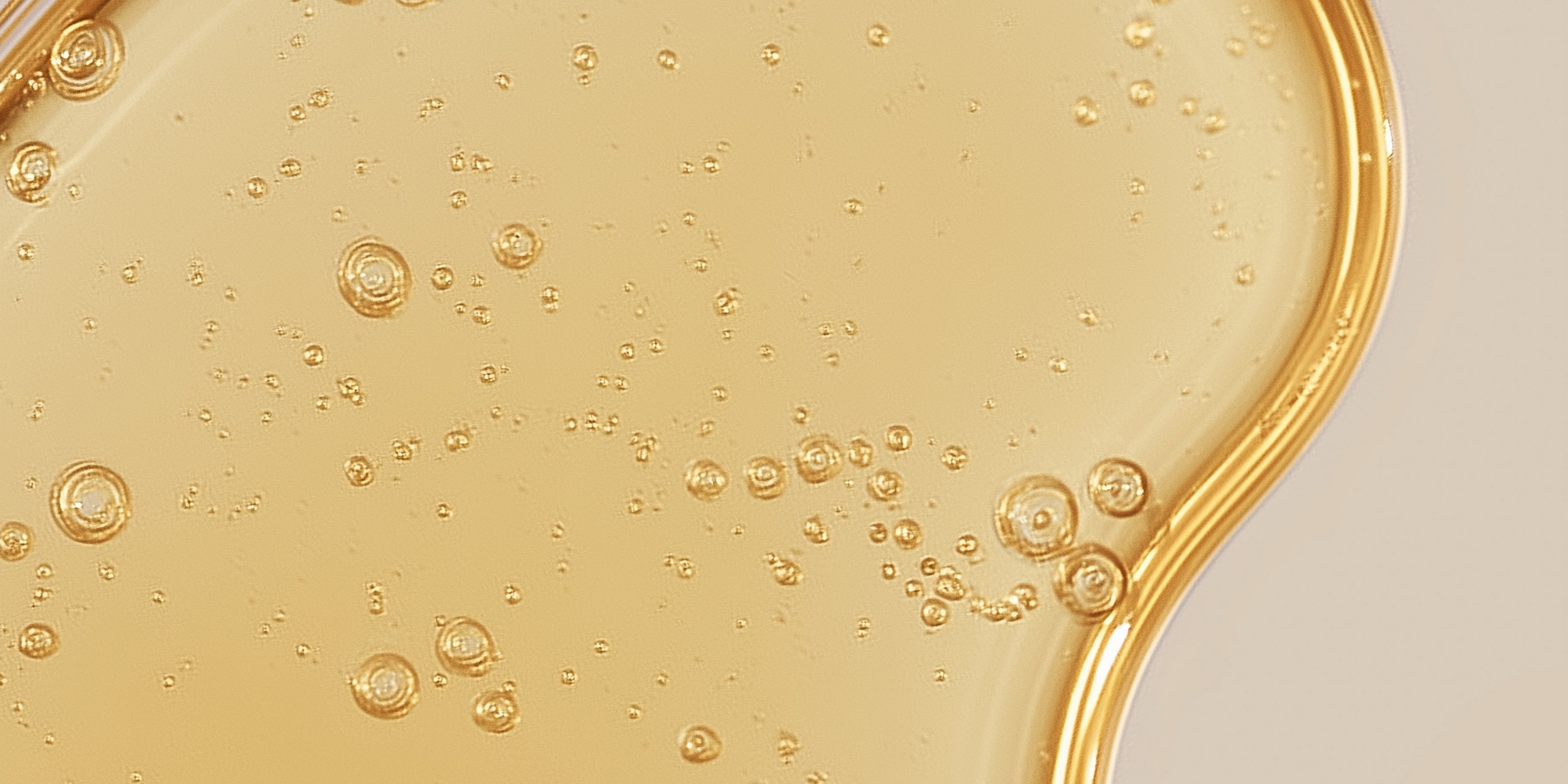 Close-up of a yellow liquid oil with bubbles on a beige background