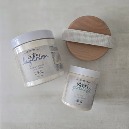 Two containers of skincare products with labels and a wooden dry brush on a light background