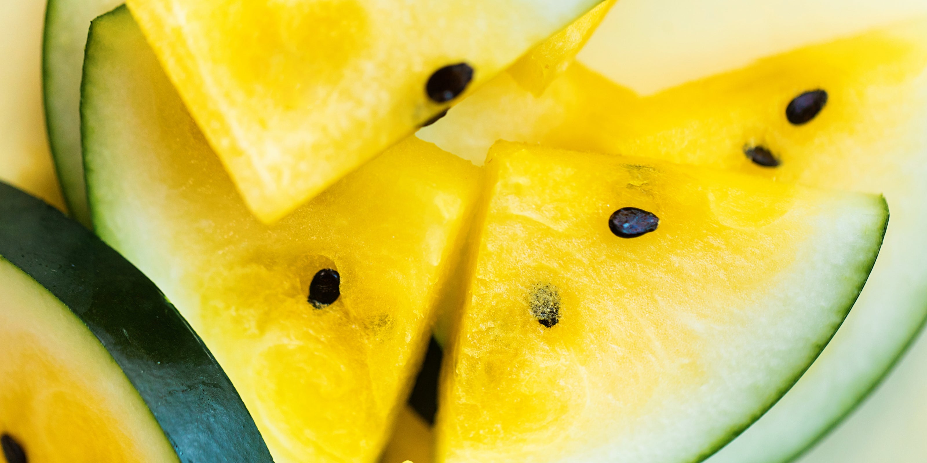 Close-up of sliced yellow watermelon with green rind.