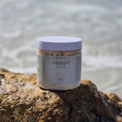 Container of On Island Time bath infusion on a rock with water in the background