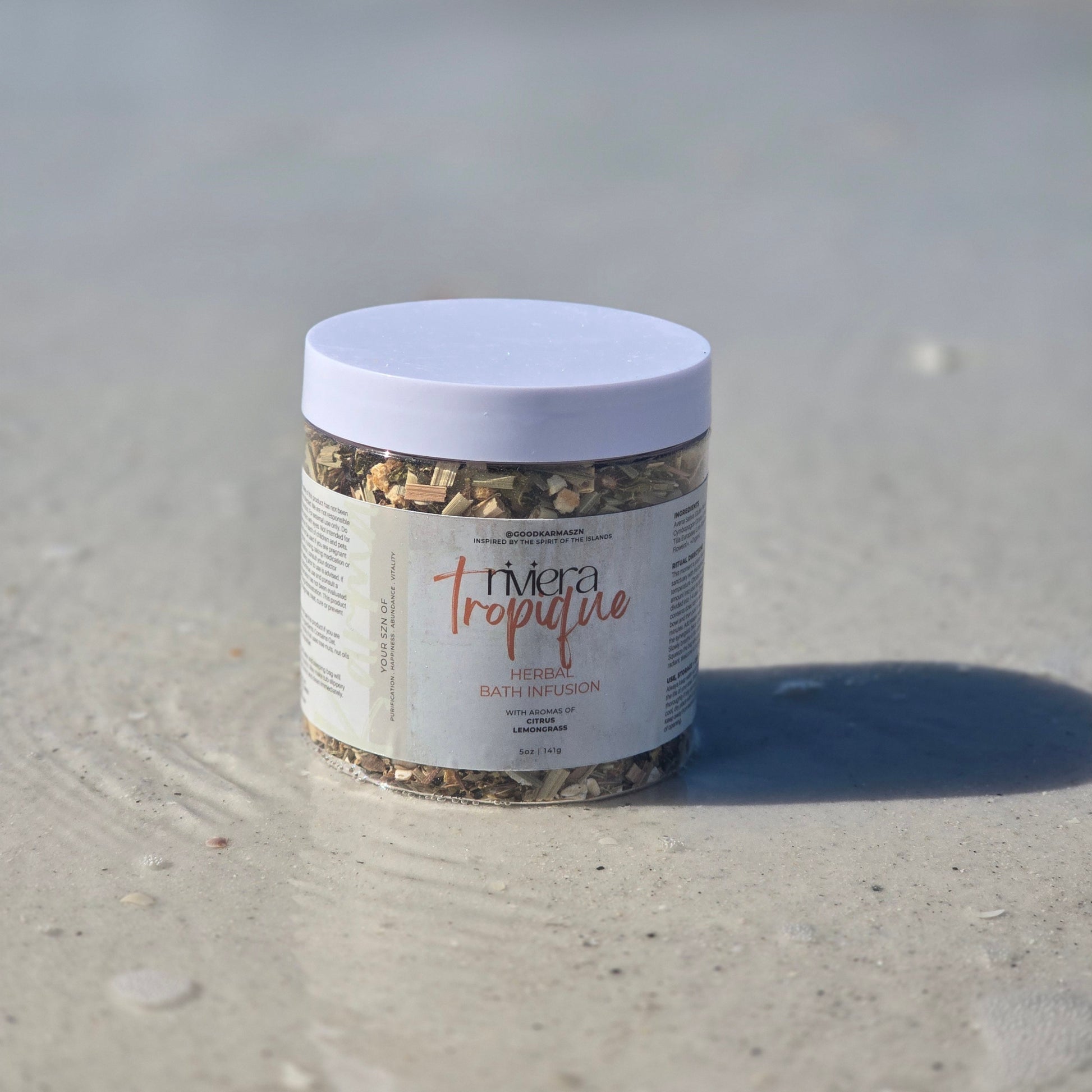 Container of herbal bath infusion named Riviera Tropique on the wet sand
