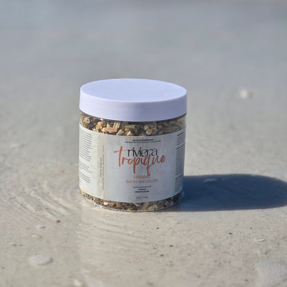 Container of herbal bath infusion named Riviera Tropique on the wet sand
