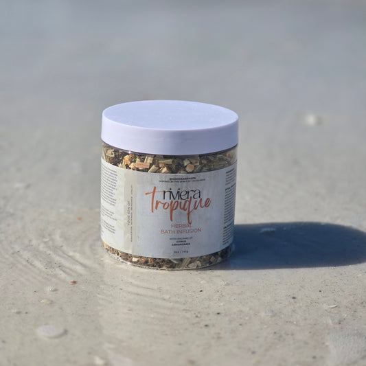 Container of herbal bath infusion named Riviera Tropique on the wet sand