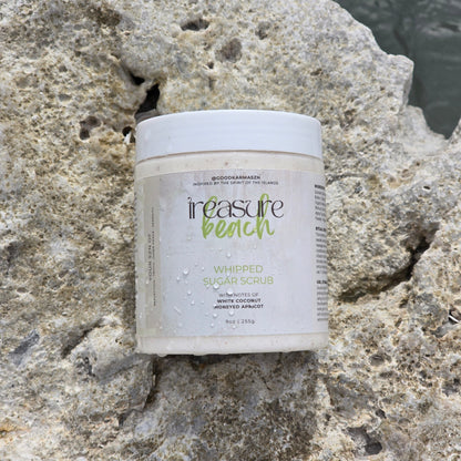 A container of whipped sugar scrub named Treasure Beach on a rocky surface