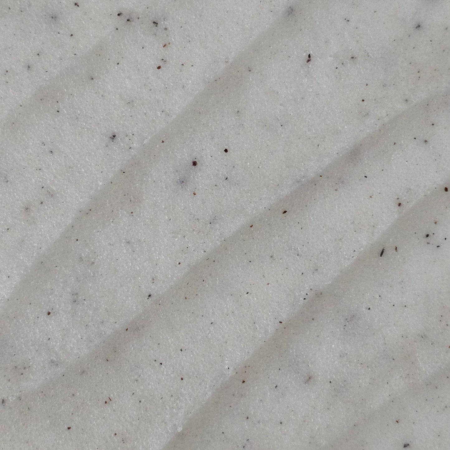 Close up of cream colored whipped sugar scrub texture with flecks of finely ground coconut shell