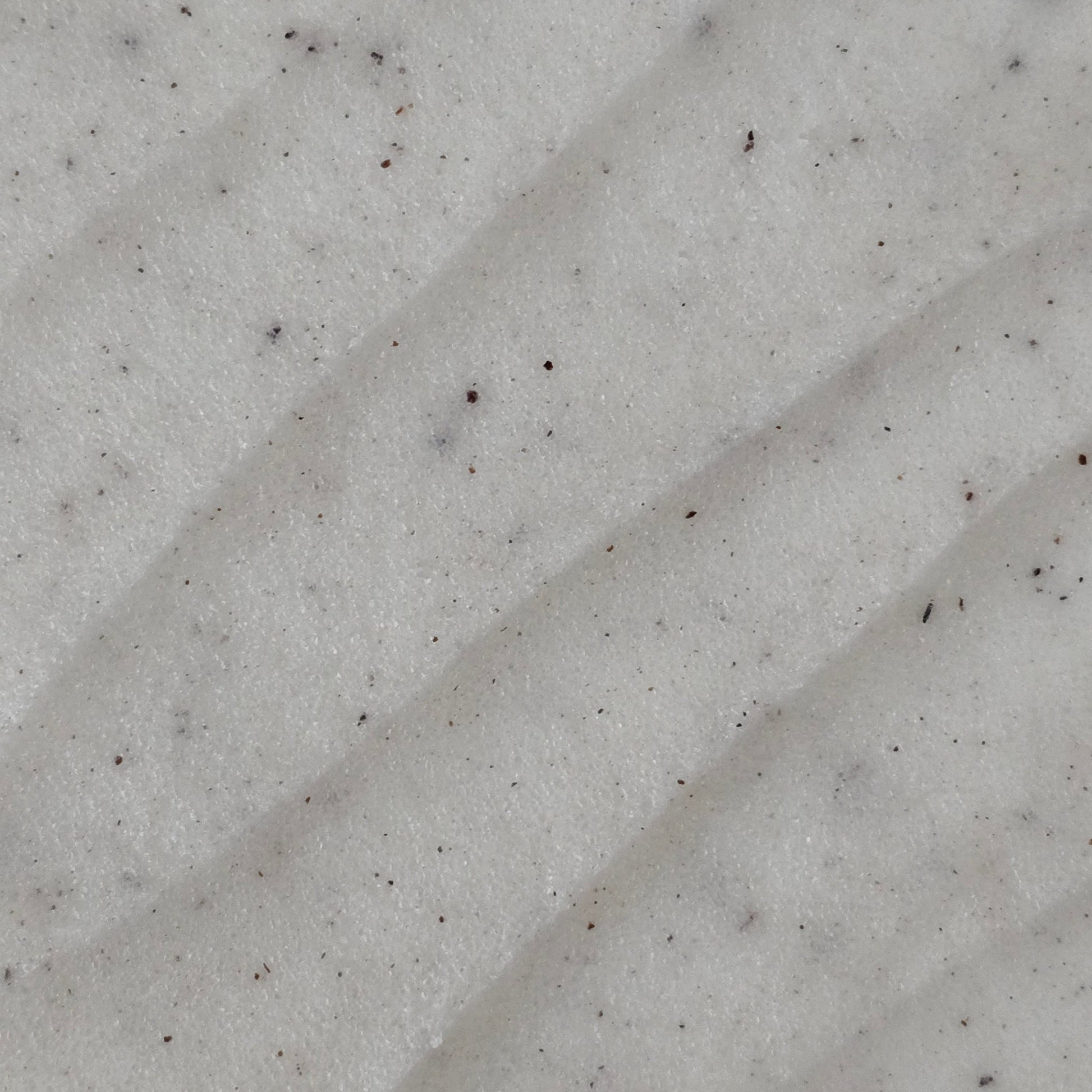 Close up of cream colored whipped sugar scrub texture with flecks of finely ground coconut shell