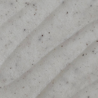 Close up of cream colored whipped sugar scrub texture with flecks of finely ground coconut shell