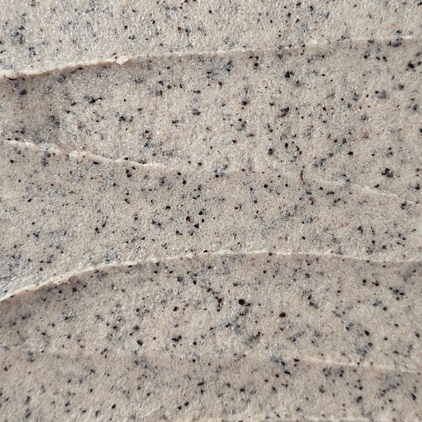 Close up of light brown whipped sugar scrub texture with flecks of finely ground coffee.