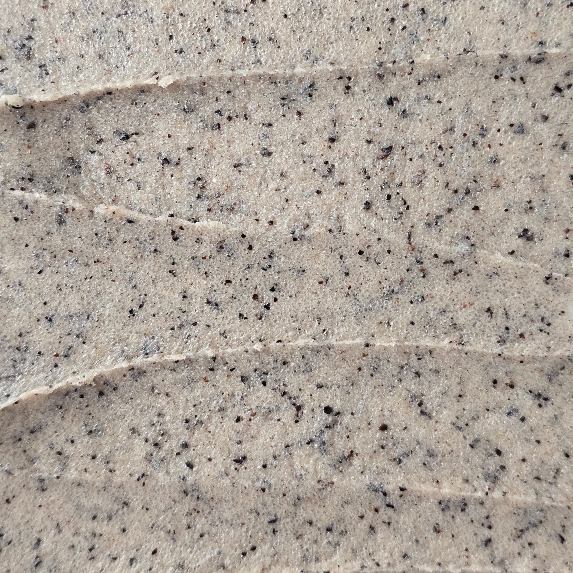Close up of light brown whipped sugar scrub texture with flecks of finely ground coffee.