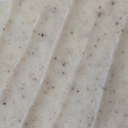 Close up of beige whipped sugar scrub texture with flecks of finely crushed cupuaçu seeds